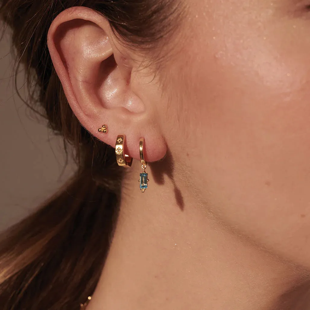 MURKANI - Huggie with Hanging Blue Topaz  Baguette in 18KT Yellow Gold Plate
