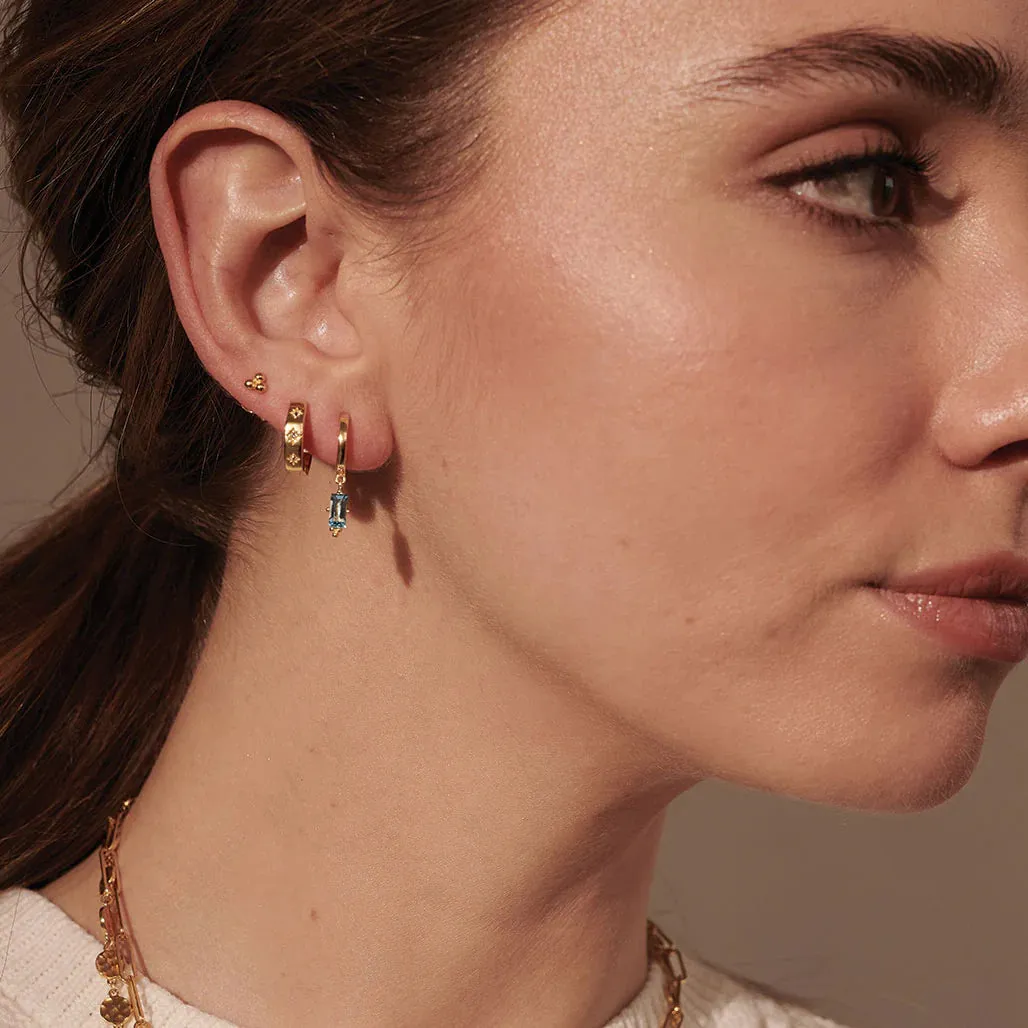 MURKANI - Huggie with Hanging Blue Topaz  Baguette in 18KT Yellow Gold Plate